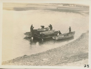 Image of Men working aboard small boats. Two boats carry smaller boats.